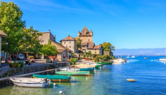 Photo d'un petit port de pêche en Huate-savoie avec des barques amarrées et des habitation en 2eme plan