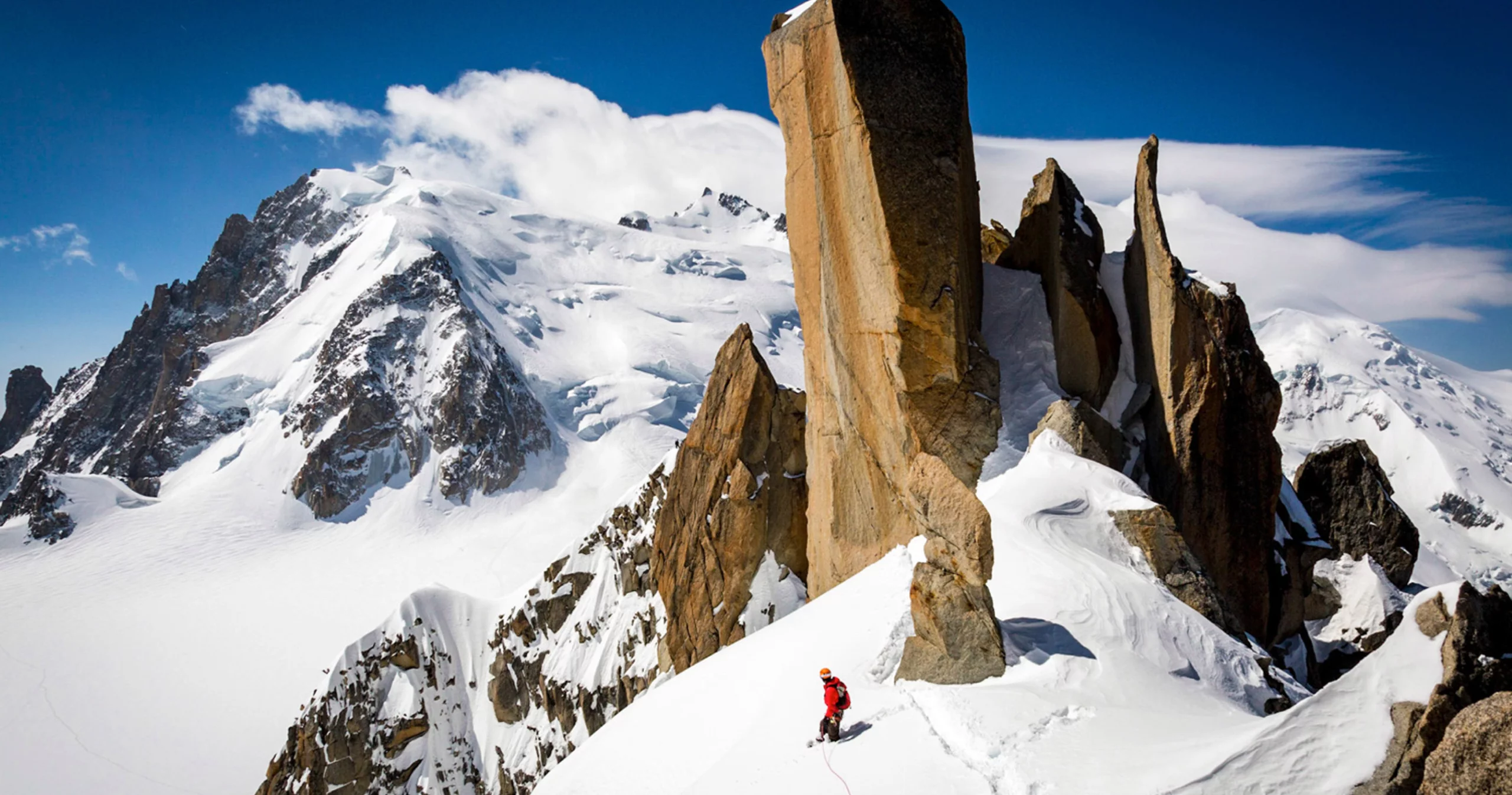 Photo d'un alpiniste au sommet d'une montagne rocailleuse enneigée