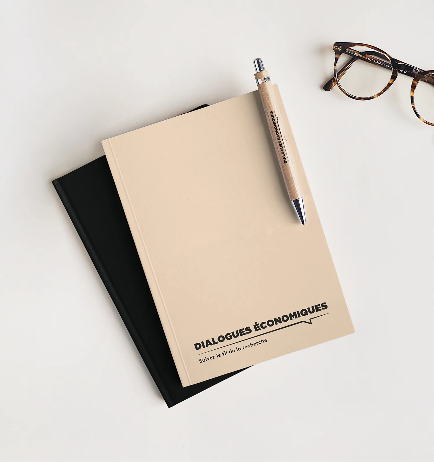 Photo du stylo et du carnet de notes dialogues économiques, de couleurs noire et beige et parés du logo