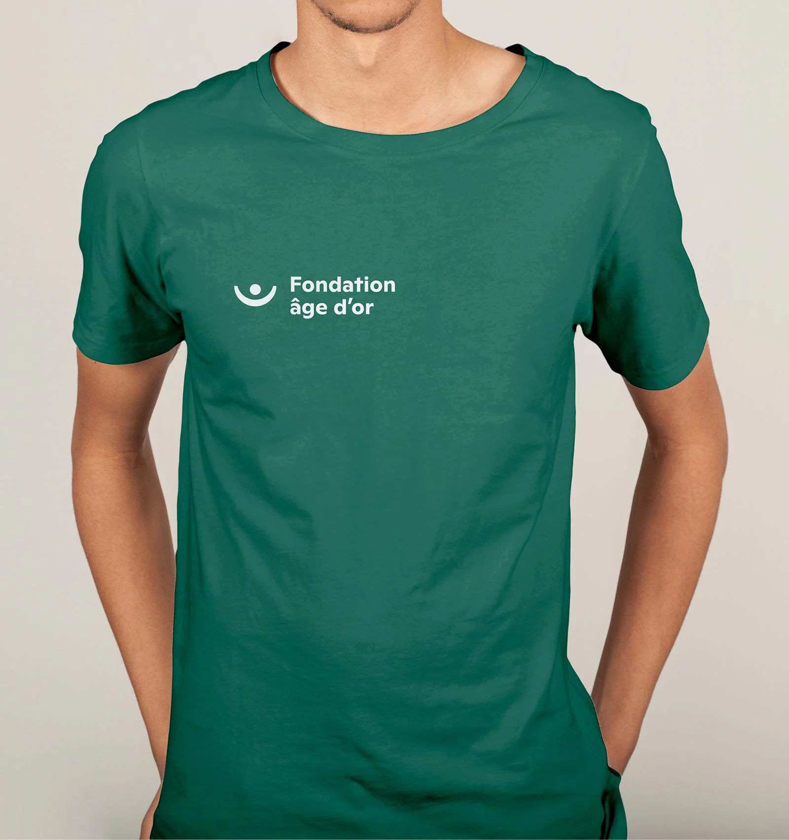 Homme portant un t-shirt vert avec le logo Fondation âge d'or en blanc en haut à gauche