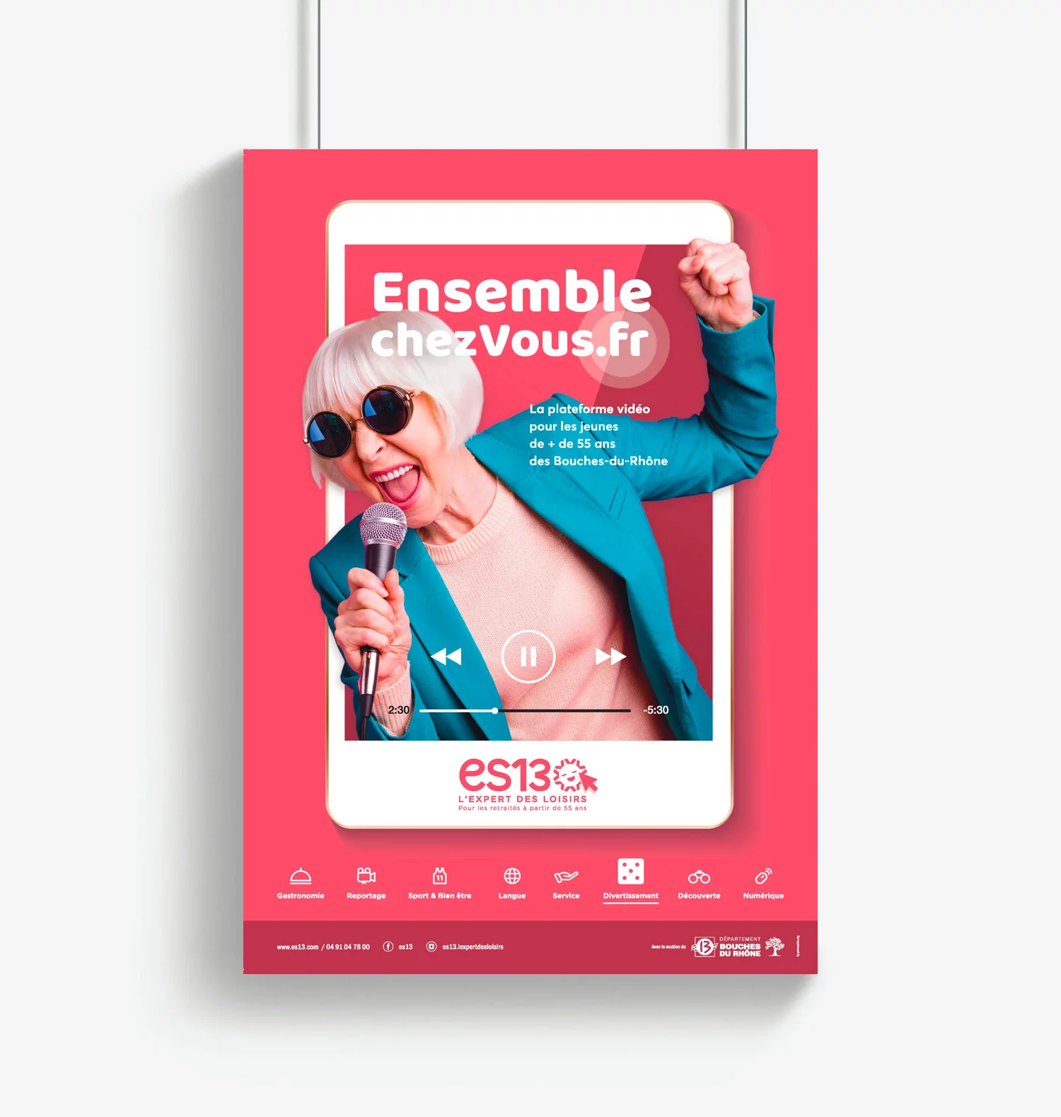 Affiche clef de la campagne ensemble chez vous, format vertical. Une femme senior chante avec un micro, lève le poing et sort d'une grande tablette, couleur dominante rose