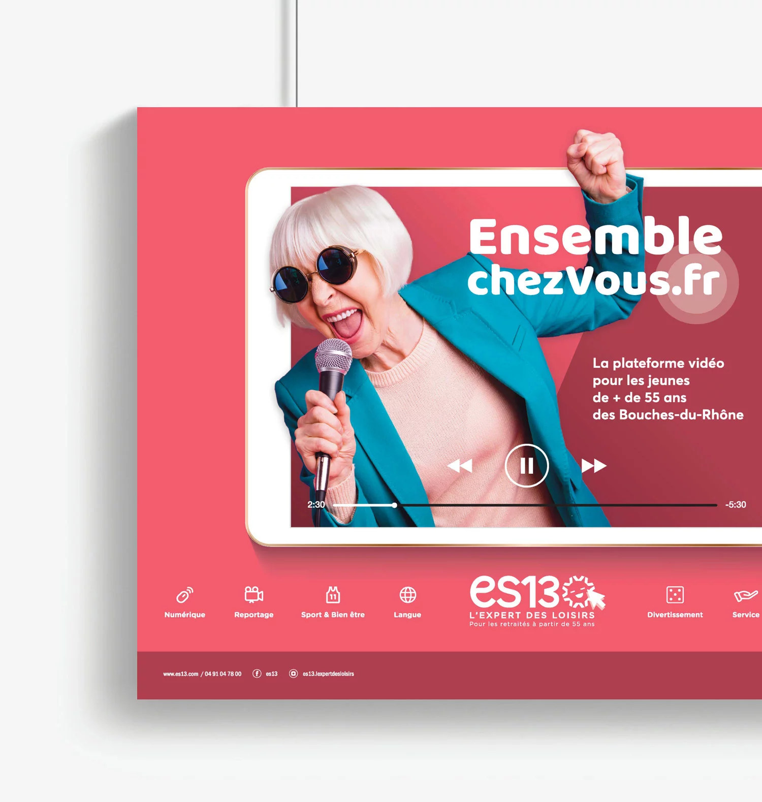 Affiche clef de la campagne ensemble chez vous, format horizontal. Une femme senior chante avec un micro, lève le poing et sort d'une grande tablette, couleur dominante rose