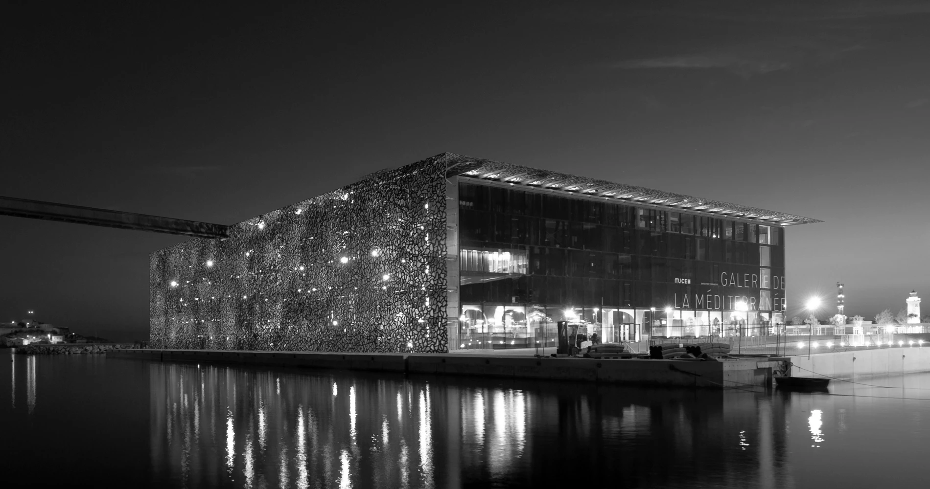 Photographie de nuit du Mucem, avec le port de Marseille en perspective